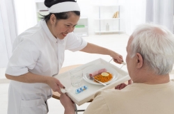 caregiver serving food to an elderly man